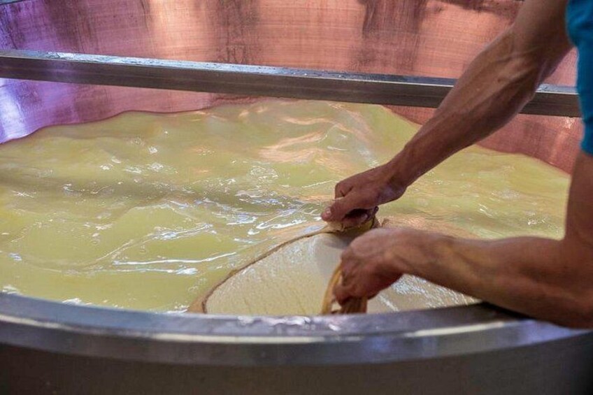 A person working with a large, round, metallic container filled with a yellowish liquid. 2