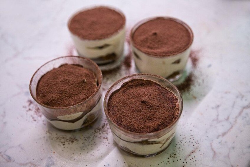 Vier kleine Gläser mit mehrschichtigem Dessert, bestäubt mit Kakaopulver. 5