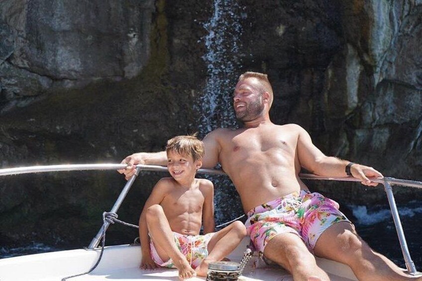 A man and a child on a boat with a rocky cliff in the background. 3