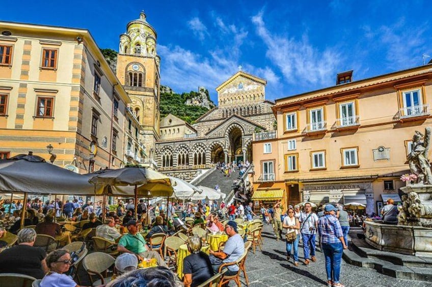 A bustling square with historic architecture, outdoor cafes, and a prominent church. 3