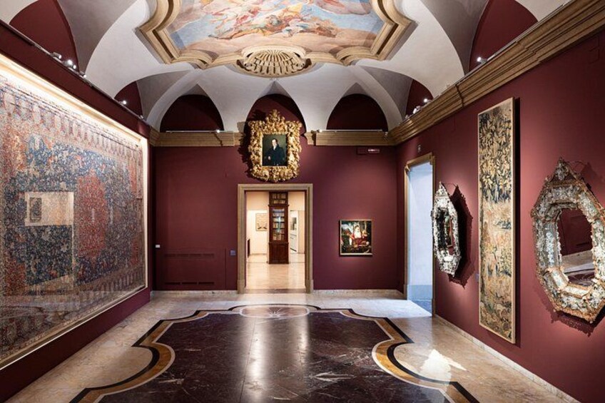 Ett konstgalleri med ett stort, mattbeklätt golv, en takmålning och flera inramade konstverk. 5