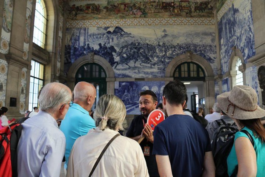 A group of people inside a building with a large mural on the wall. 5