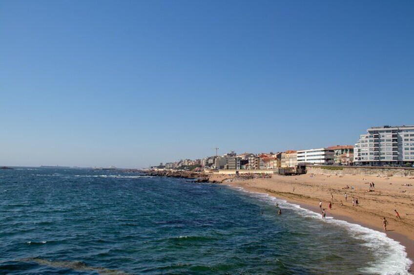 A beach with waves, people, and buildings along the shore. 2