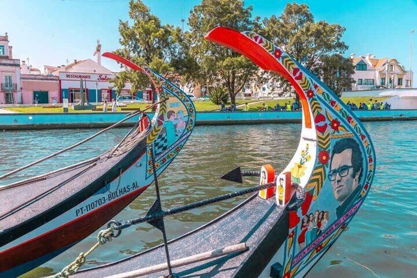 Two decorated boats on a calm body of water with buildings and trees in the background. 4