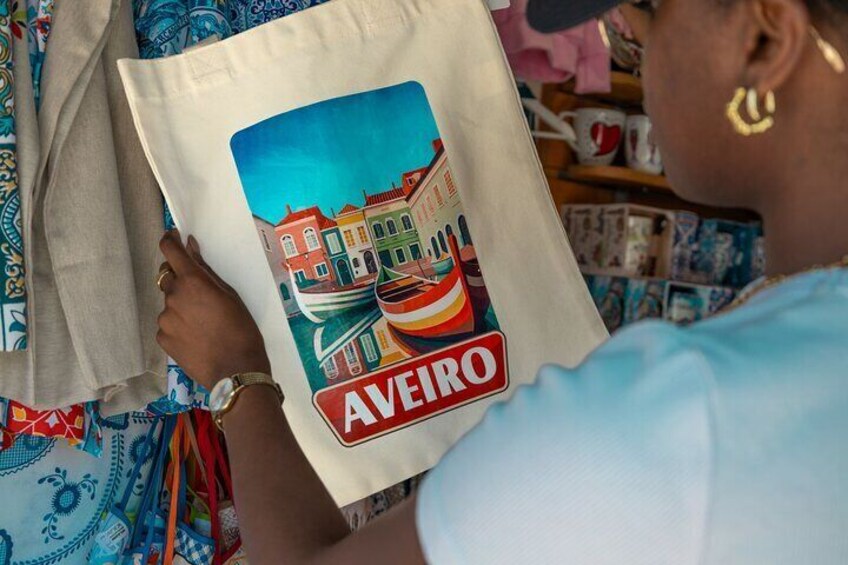 A person holding a tote bag with a cityscape design and the word "AVEIRO" on it. 4