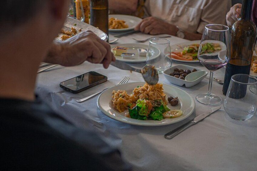 A dining table with plates of food, wine glasses, and a bottle. 3