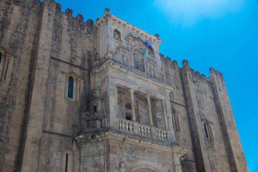 Un grand bâtiment historique en pierre, doté d’un balcon imposant et de fenêtres en arc de cercle. 2