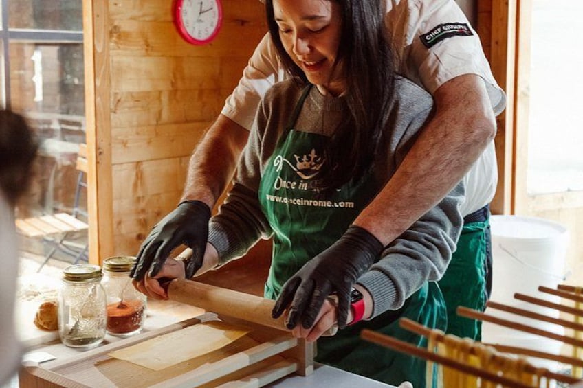 Une personne portant un tablier vert, qui travaille avec des bocaux et des outils en bois sur une table. 2