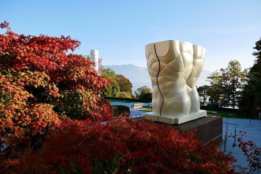 Une sculpture moderne dans un parc, avec des feuilles d’automne et une montagne en arrière-plan. 3
