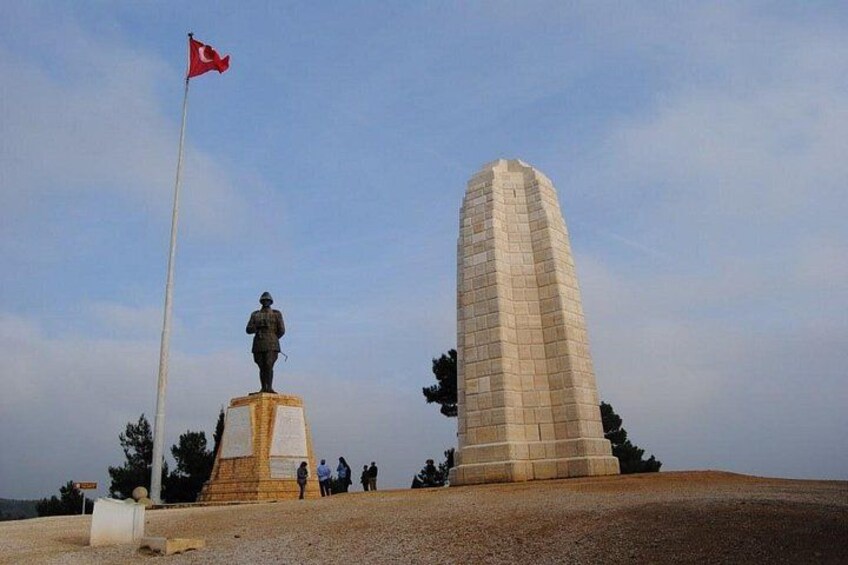 Ett monument med en flagga, en staty och en hög byggnad. 5