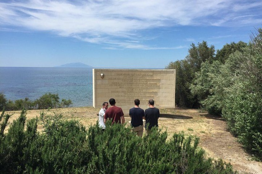 En grupp människor som står framför ett stenmonument vid havet. 3