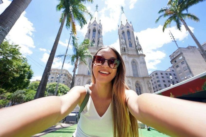 Una persona tomándose un selfie con una catedral y palmeras al fondo. 1