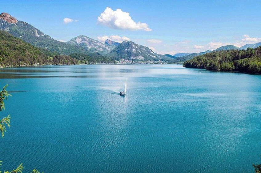 A calm lake with a sailboat, surrounded by mountains and clear skies. 2