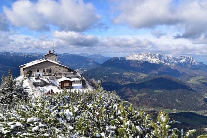 A mountain lodge with snow-covered trees and a view of snow-capped mountains in the background. 1
