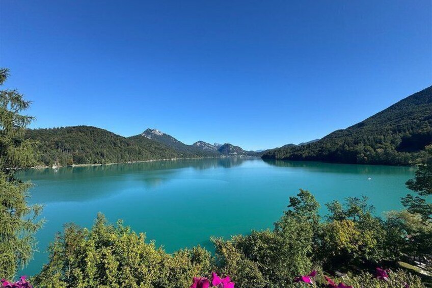 Un lac paisible, entouré de collines et de montagnes boisées, sous un ciel bleu dégagé. 2