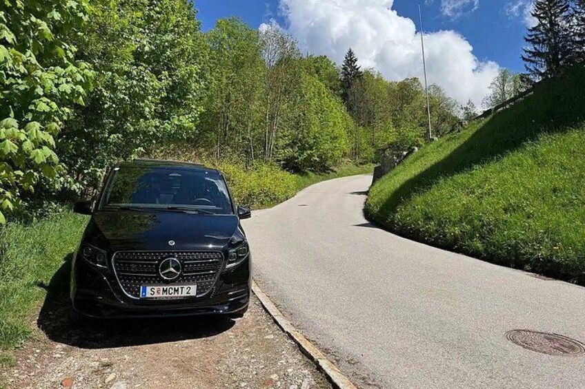 A black car parked on a winding road surrounded by greenery. 3