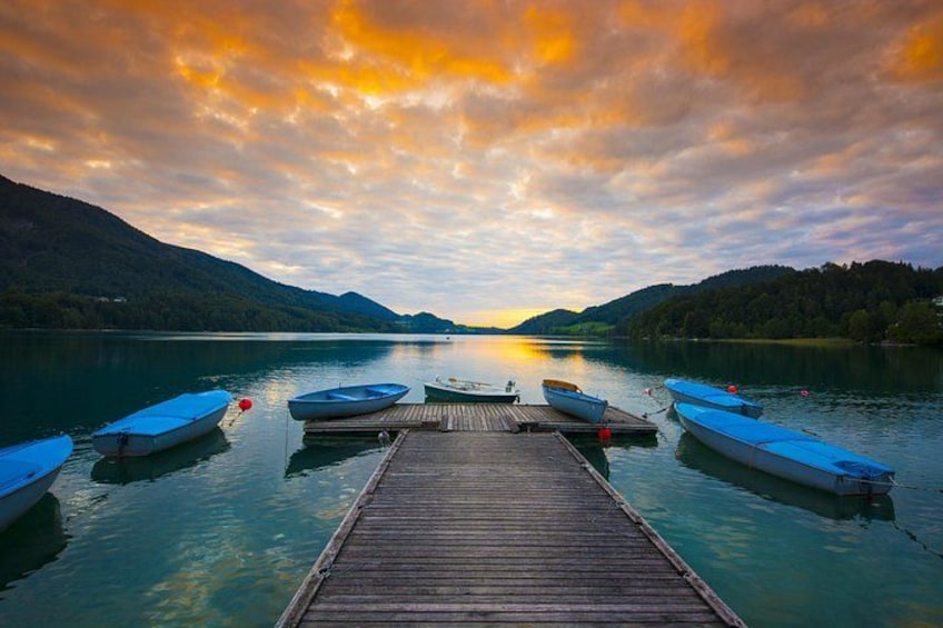 A wooden dock extending into a calm lake with boats moored at the end. 4