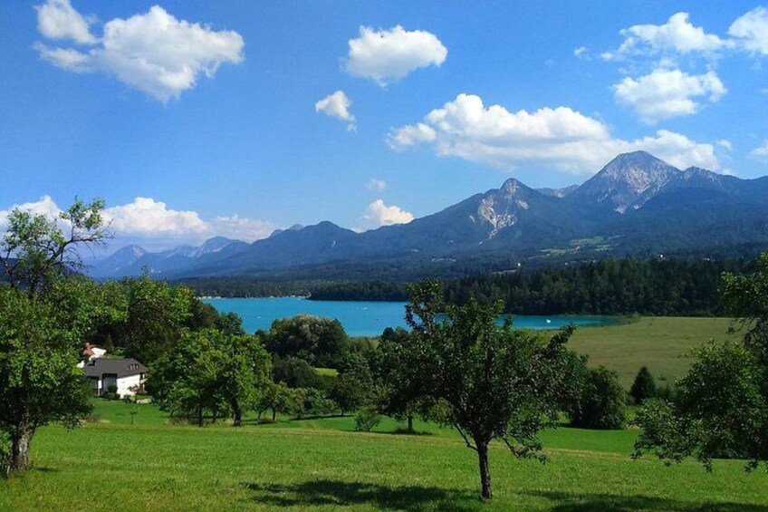 A lake surrounded by mountains, a house, and green fields. 5