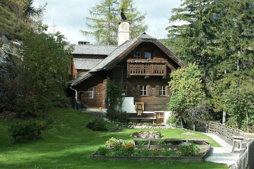 Una casa de madera con techo inclinado, rodeada por un jardín cuidado y una valla de madera. 4