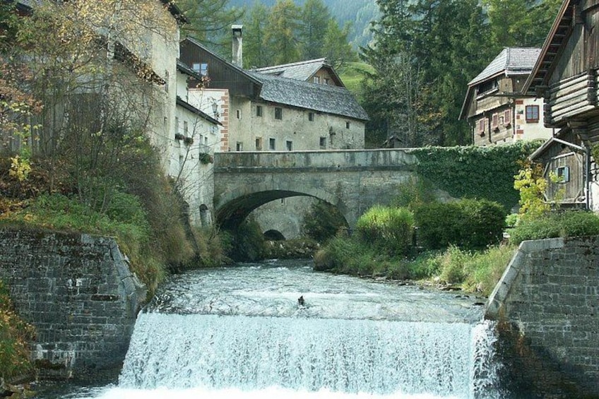 Un puente de piedra sobre un río, rodeado de edificios y vegetación. 3
