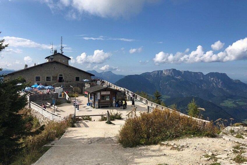 Una cabaña de montaña con una escalera de madera que lleva hasta ella, rodeada por un paisaje montañoso. 3