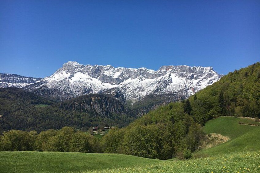 Une chaîne de montagnes aux sommets enneigés, une vallée verdoyante et un petit village. 4