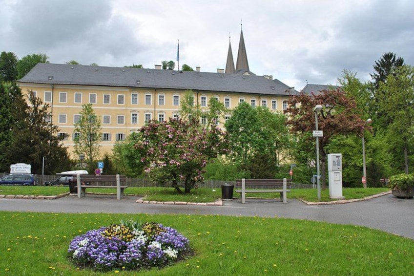 A building with a church steeple, a parking sign, a bench, and a flower bed. 4