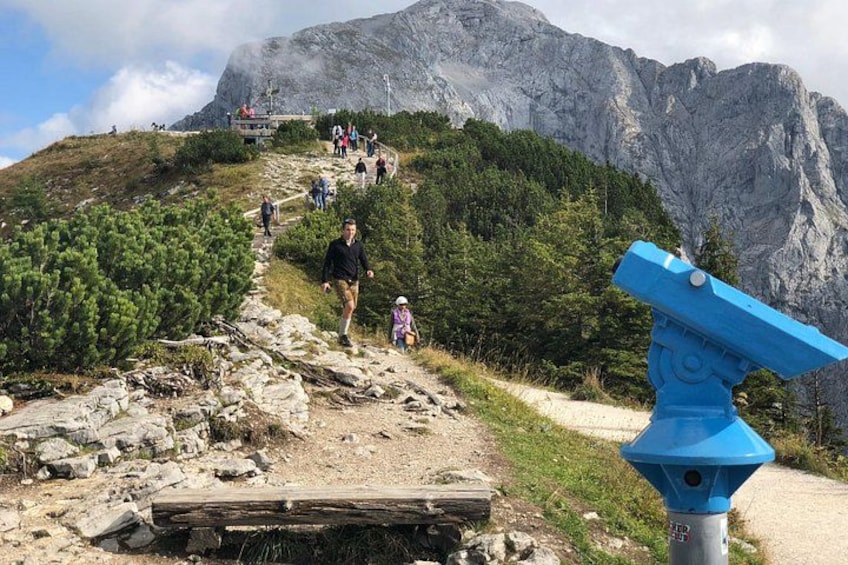 Un sentiero escursionistico con persone che salgono su una montagna, un osservatorio blu e terreno roccioso. 4