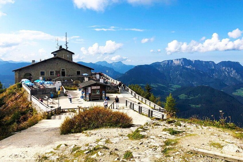 A mountain observation tower with a paved walkway, surrounded by rocky terrain and distant mountains. 1