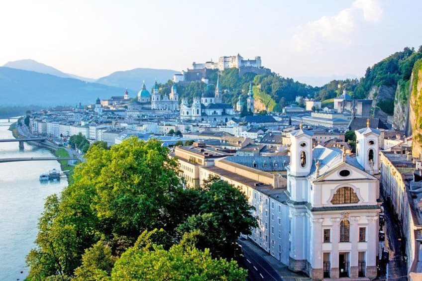 A cityscape with a river, historic buildings, and a castle on a hill. 2