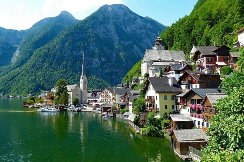 A lakeside village with traditional houses, a church, and mountains in the background. 2