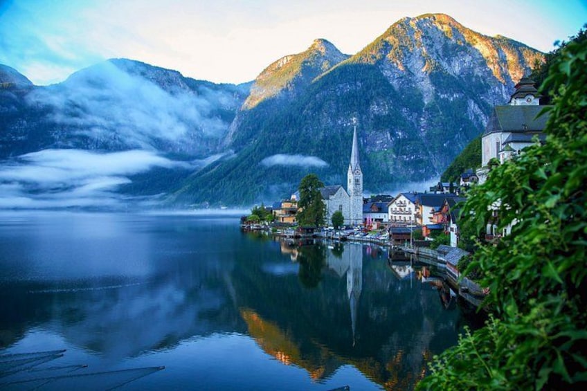 A calm lake with a church, houses, and mountains in the background. 4