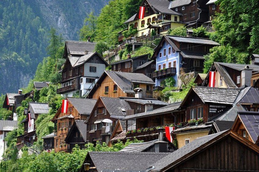 A cluster of traditional wooden houses on a hillside with red flags. 3
