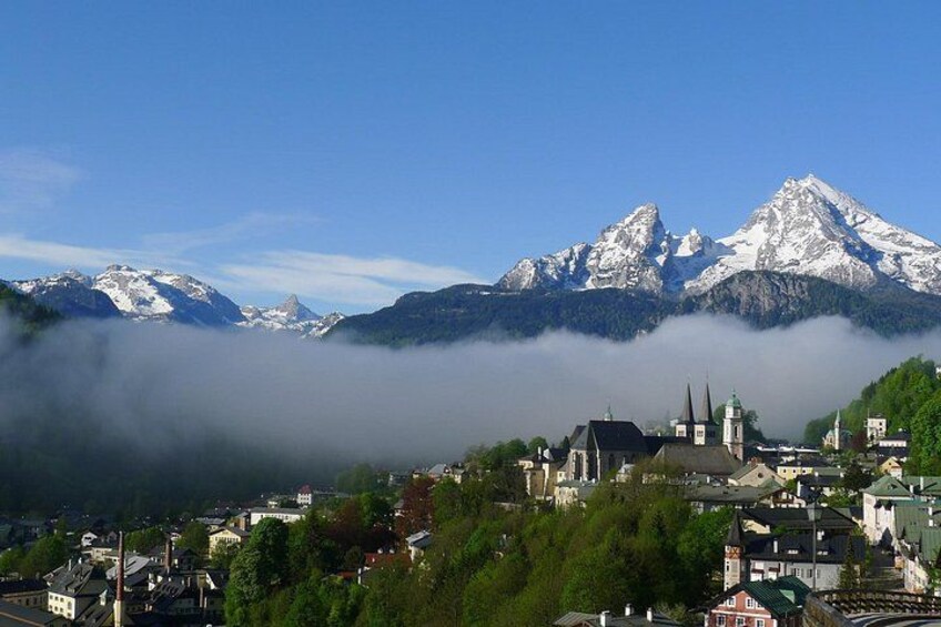 A town nestled between mountains, with snow-capped peaks and a church in the foreground. 3