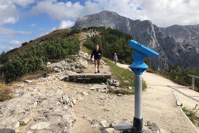 A hiking trail with rocky terrain, a wooden bridge, and a mountain backdrop. 2