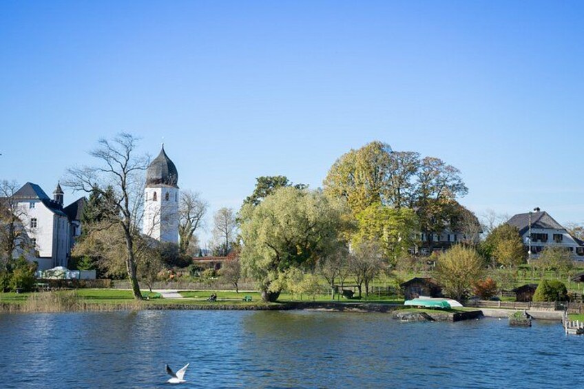 Een rustig meer met een zwaan, een kerktoren en woongebouwen. 1
