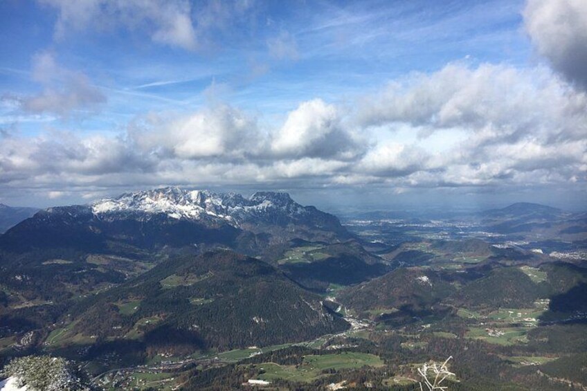 A mountainous landscape with snow-capped peaks, a valley, and a partly cloudy sky. 5