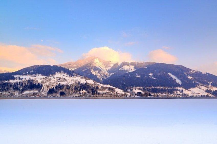 A snow-covered mountain range with a clear sky and a frozen lake in the foreground. 4