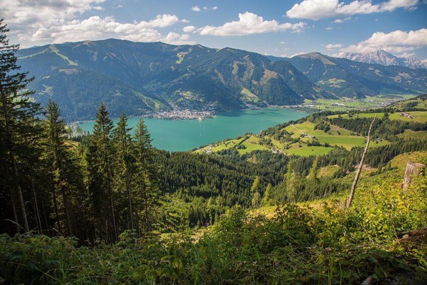 A mountainous landscape with a lake, dense forest, and distant town. 3