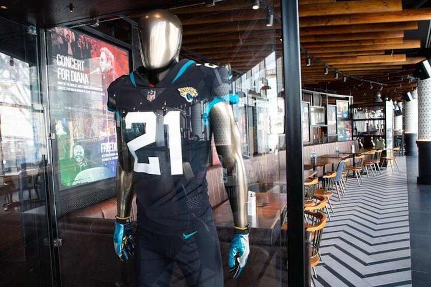 A sports-themed restaurant interior with a large glass display case, wooden ceiling, and a patterned floor. 2