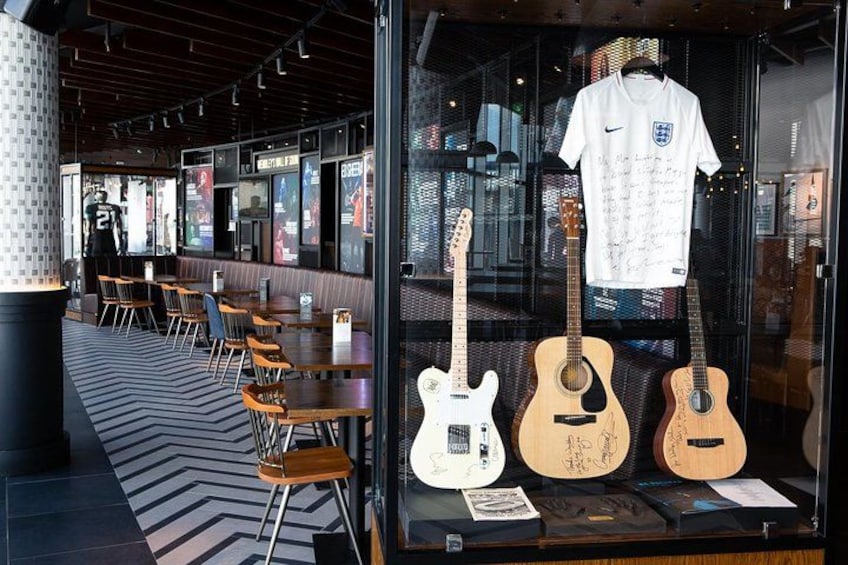 A restaurant with a glass display case containing guitars and a signed shirt. 3