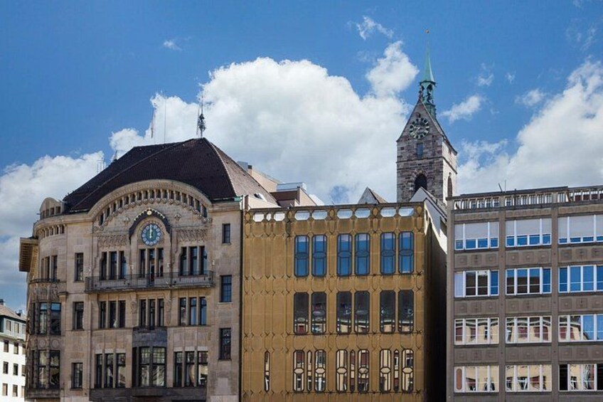 Un edificio histórico con una torre de reloj, una fachada amarilla moderna y un edificio tradicional con una aguja. 2