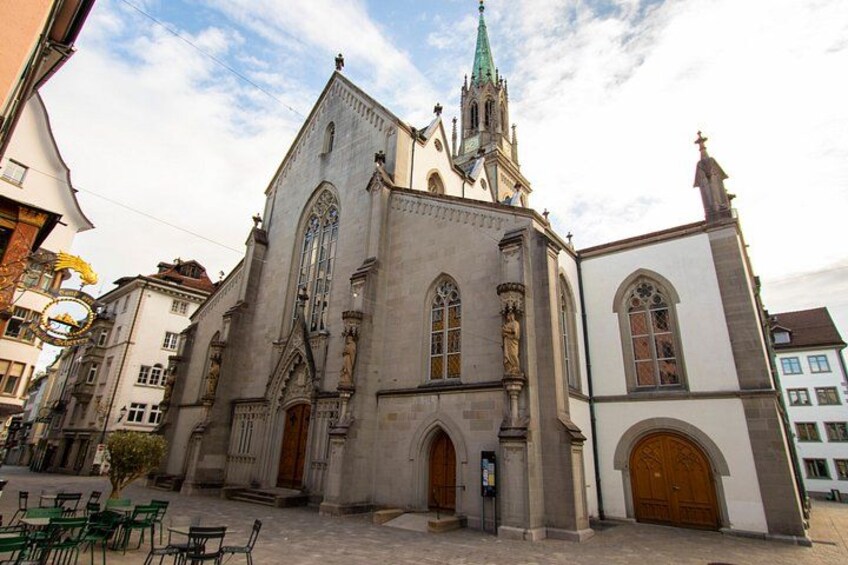 A historic church with a tall spire, large arched windows, and a prominent entrance. 4