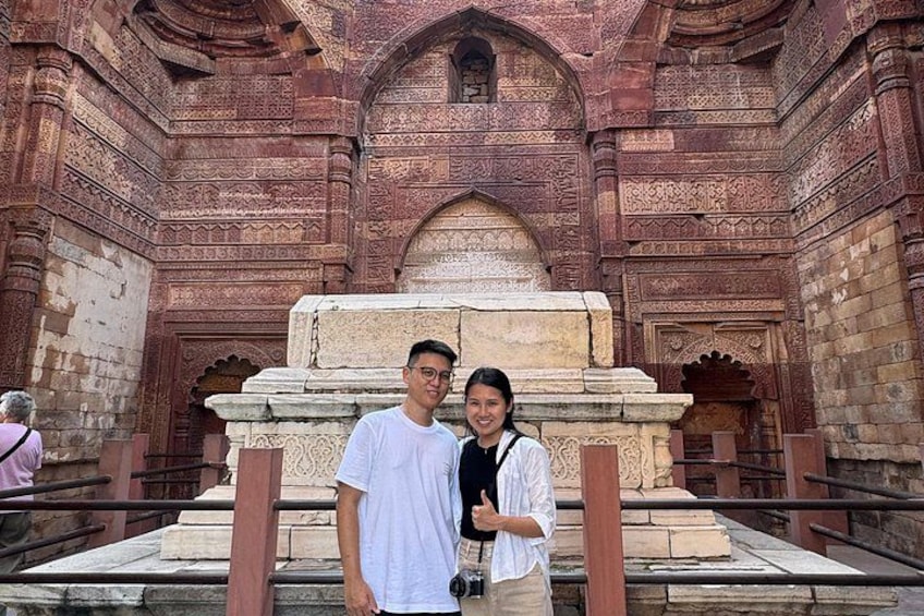 A couple standing in front of a historical building with intricate carvings and a large stone structure. 5