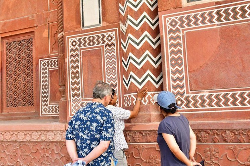 Un gruppo di persone che osserva i complessi motivi architettonici sulla facciata di un edificio. 2