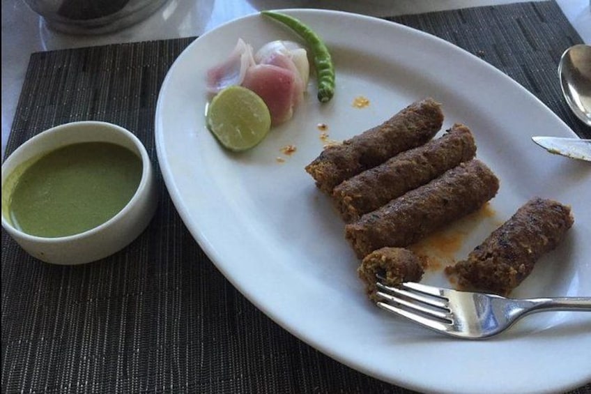A plate with four meatballs, a lime wedge, and a green sauce on a table. 4