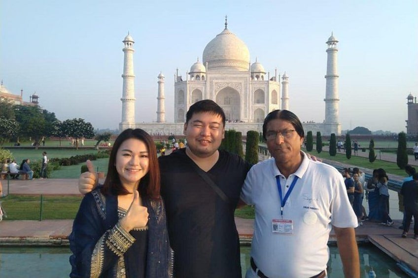 Tre personer står framför Taj Mahal, och man kan se kupolerna och minareterna i bakgrunden. 3