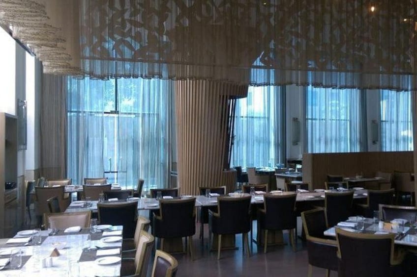 Un ristorante con tavoli apparecchiati, ampie finestre e un soffitto decorato. 5