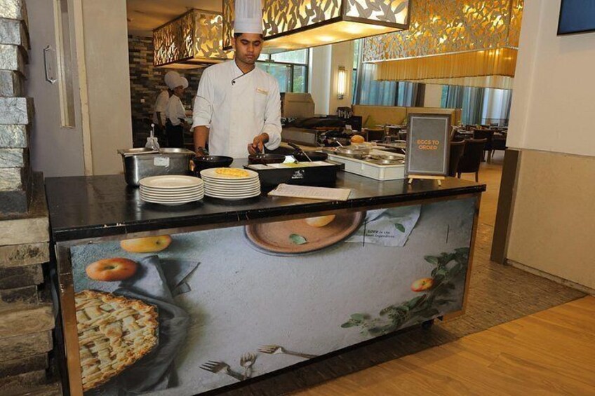 Un chef preparando comida en un mostrador de buffet con una pared decorativa que presenta ilustraciones de alimentos. 4