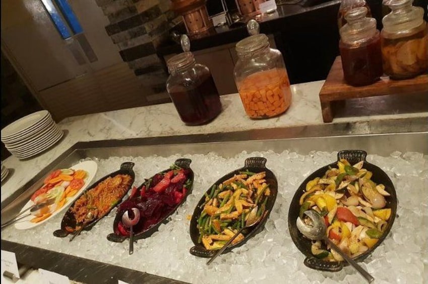 A buffet with various dishes on ice, including roasted meats and vegetables. 2
